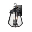 Maxim Lighting Mariner Outdoor Wall Sconce in Black with Antique Brass finish, crafted from Aluminum, mounted on a brick wall, emits a warm glow.