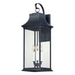 Maxim Lighting Vicksburg Outdoor Wall Sconce in black aluminum with clear glass panels, mounted on a brick wall, illuminating a patio area.
