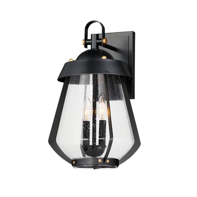 Maxim Lighting Mariner Outdoor Wall Sconce in Black with Antique Brass finish, crafted from Aluminum, mounted on a brick wall, emits a warm glow.